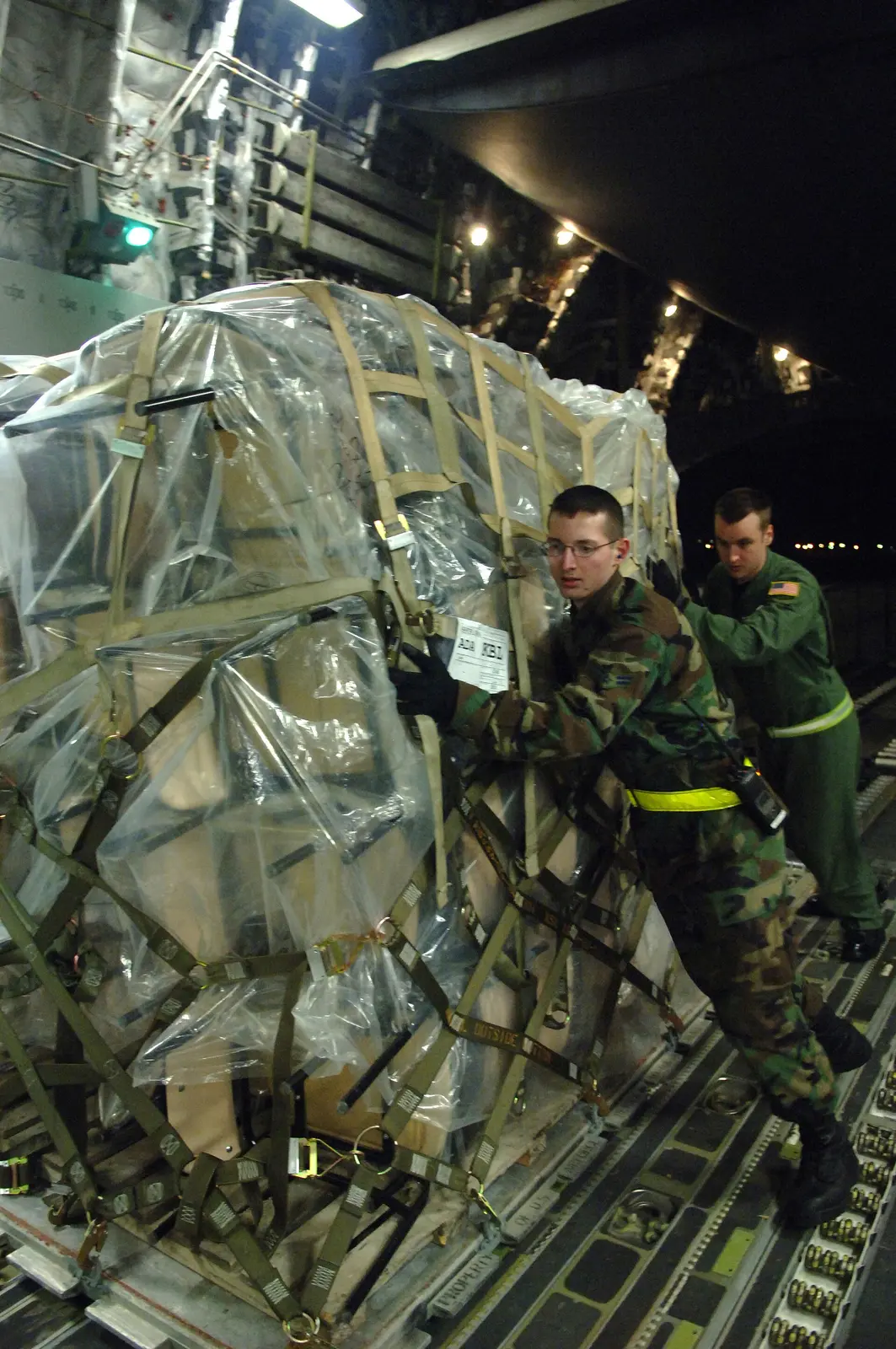 Cargo team guiding a secured pallet during aircraft loading.
